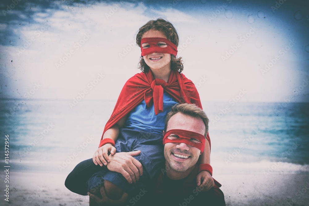 Father and son in superhero costume enjoying at sea shore