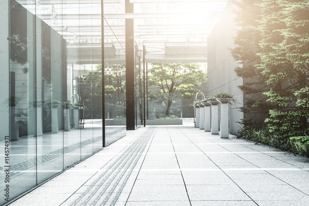 empty footpath through modern office buildings in tokyo with sun