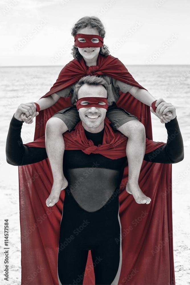 Happy father in superhero costume carrying son on shoulder