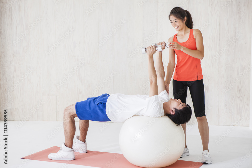 Men have a dumbbell exercise with the balance ball