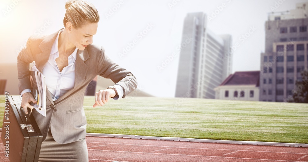 Composite image of businesswoman looking at her watch