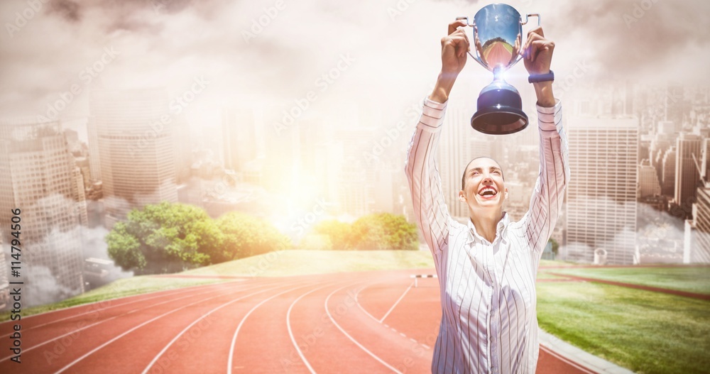 Composite image of successful businesswoman lifting a trophy