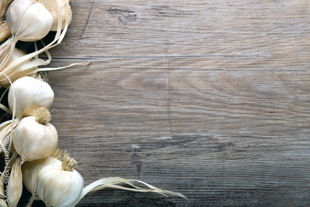 String of garlic on wooden board background, copy space