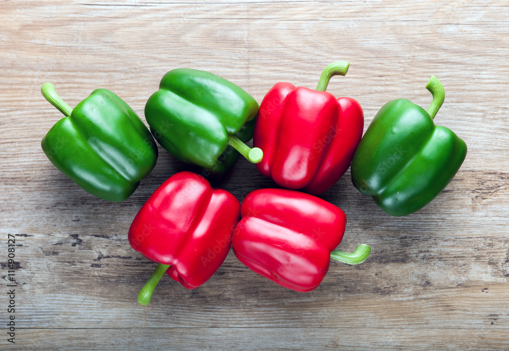 Fake red and green peppers on wooden board background