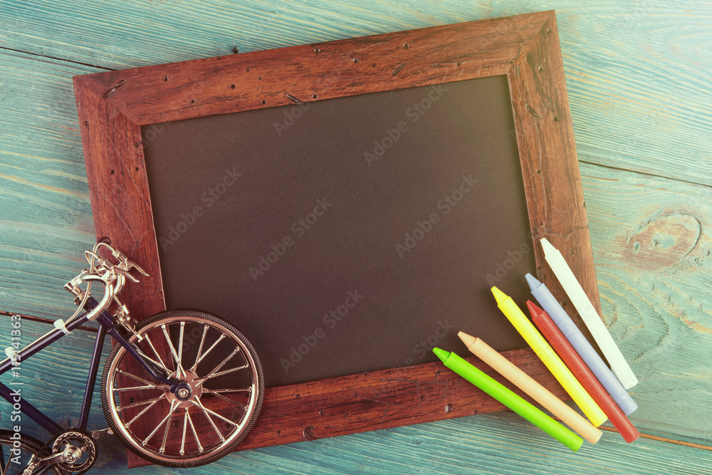 empty chalkboard with copyspace and colorful crayons on wooden table