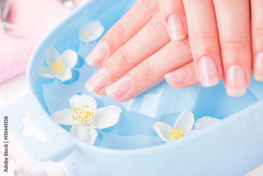 Beautiful womans hands with manicure in bowl of water