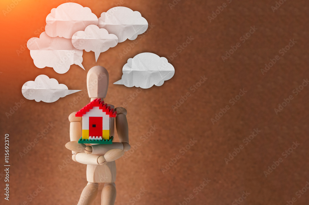 wooden man holding home model with speech bubble for copy space.