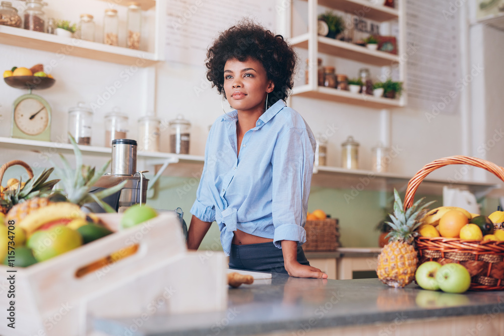 Attractive young woman standing at juice bar counter