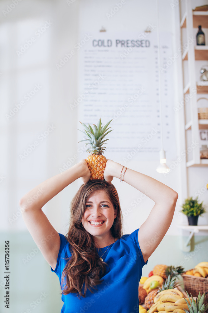 Woman holding a pineapple on her head at juice bar