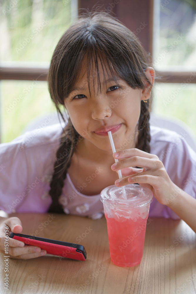 快乐的亚洲女孩在咖啡馆喝冰草莓奶昔