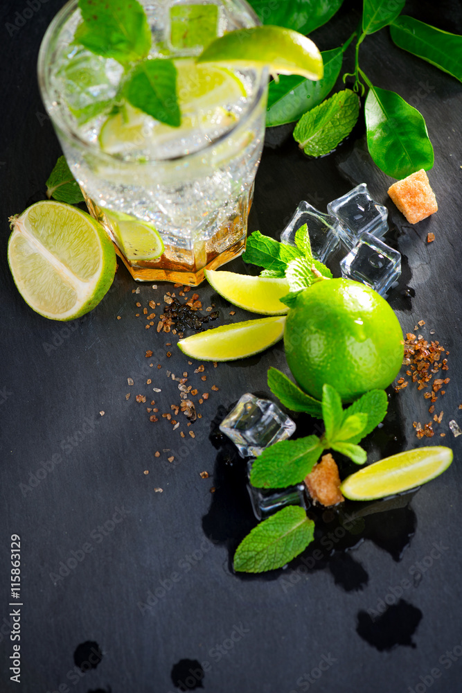 Mojito cocktail on a table. Summer cocktail with rum, lime, mint, ice cubes and brown sugar