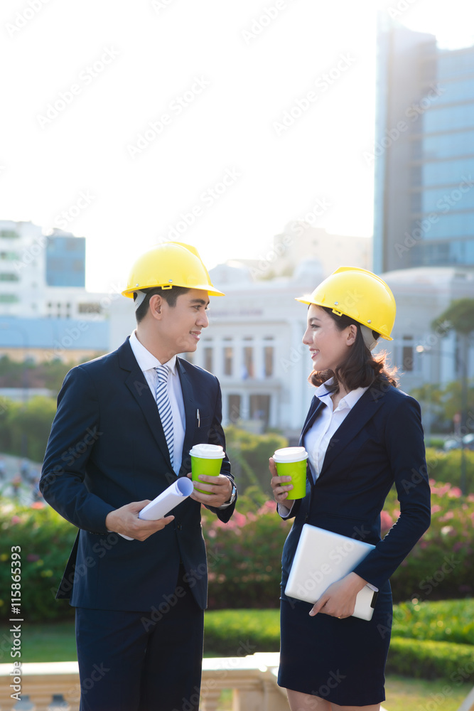 两位建筑师在街上散步和交谈。阳光明媚，伦