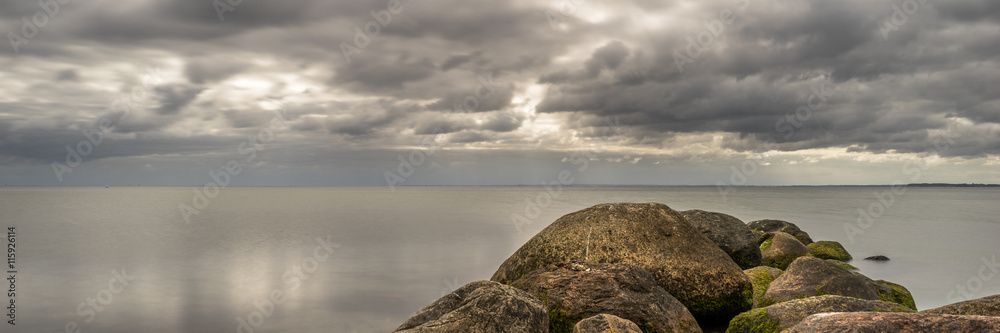 Beautiful coastal scenery, stones and sandy beach under a cloudy sky, relax and chill, panorama