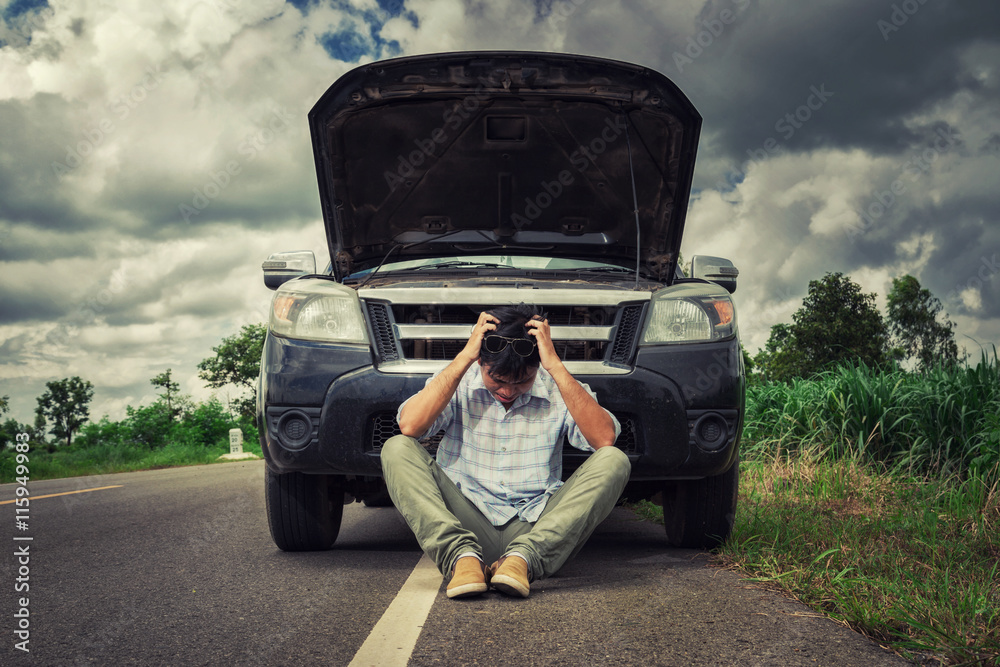 young stressed man having trouble with his broken car looking in frustration on failed engine