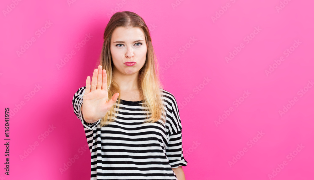 Young woman making a stop pose on a pink background