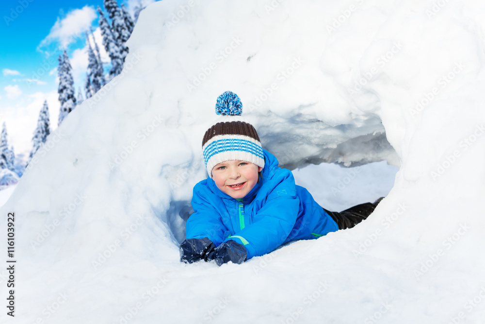 小男孩在公园的雪地隧道里爬行