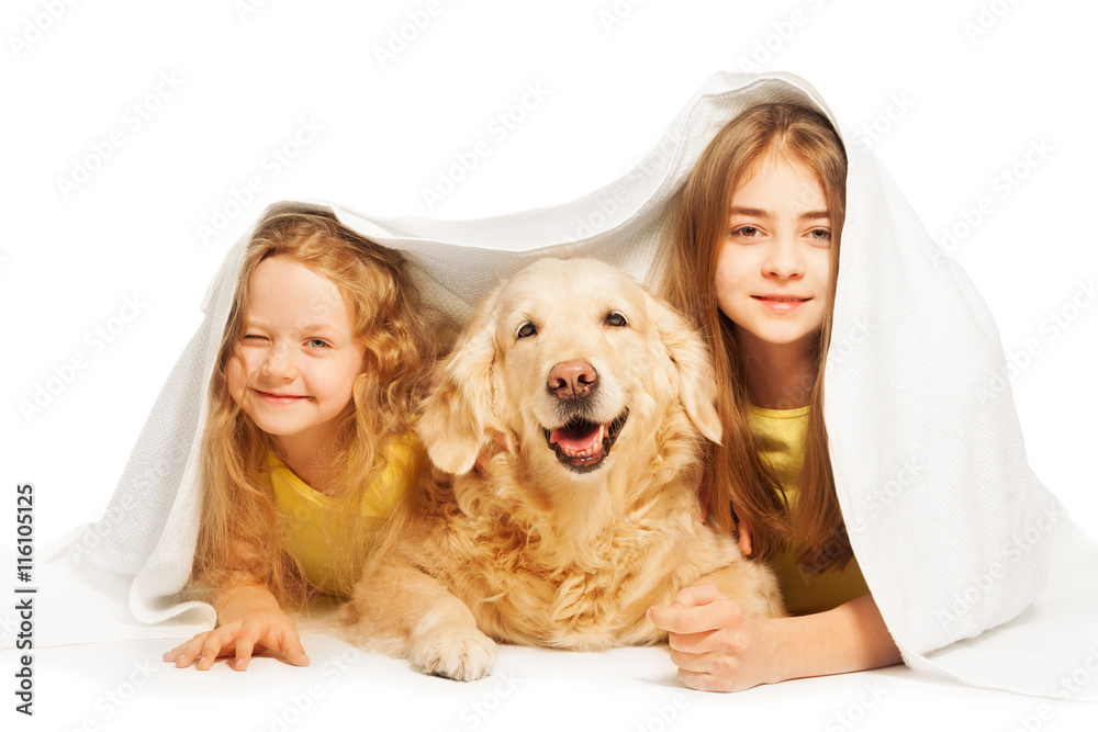 Cute girls hiding under the white blanket with dog