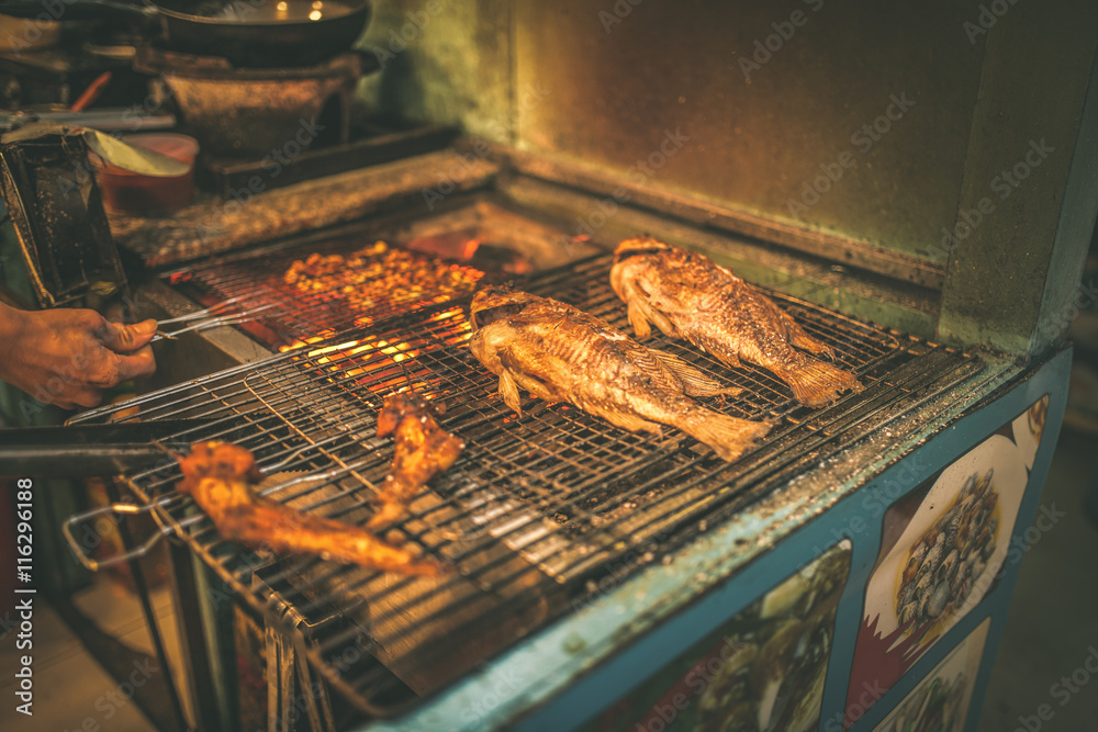 Street Food in Saigon, Vietnam. Hot fish on a grilling pan