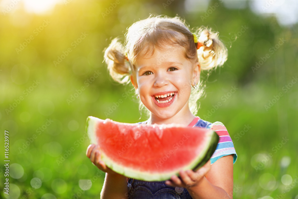 Happy child girl eats watermelon