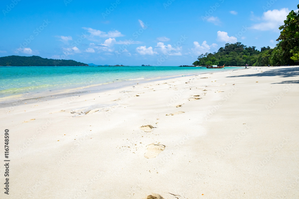 Footprints on white sand and crystal sea at lipe island