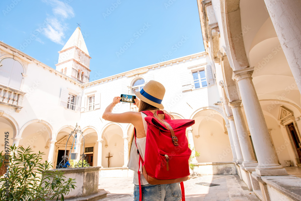 年轻的女性旅行者用手机拍摄皮兰镇古老的修道院。在斯洛文尼亚旅行