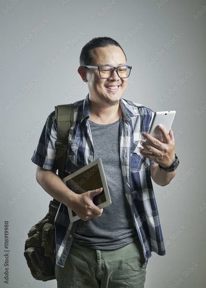 微笑的亚洲男子拿着智能手机和数字桌子