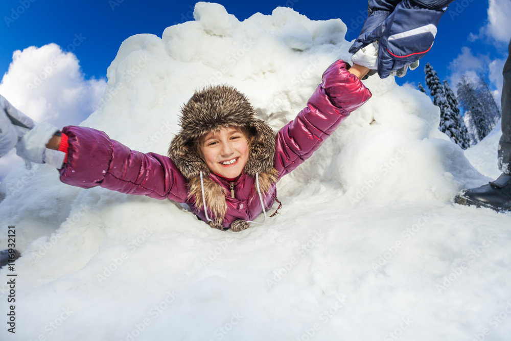 孩子们正把微笑的女孩从雪洞里拉出来