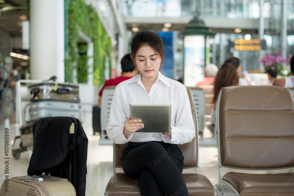 Asian young business woman at the airport, using her tablet computer