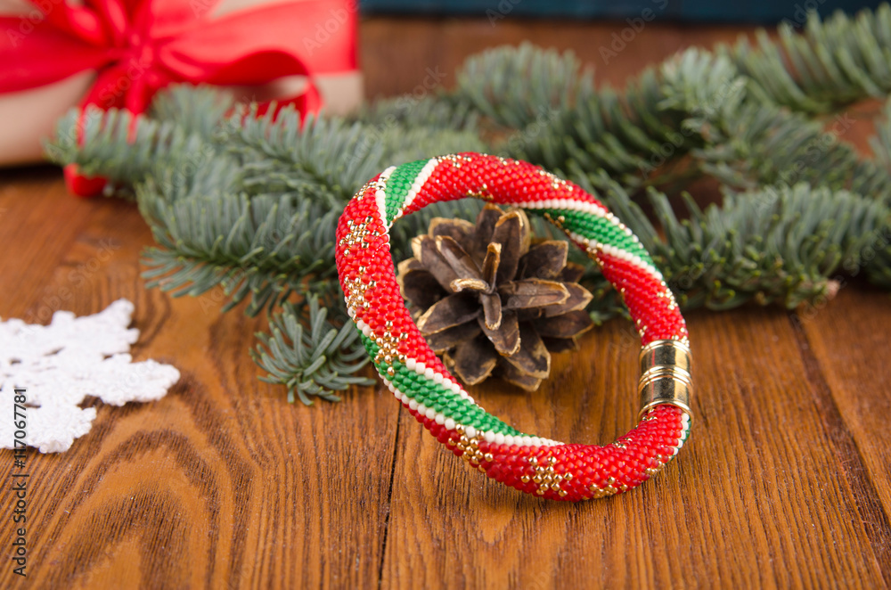 Beadwork handmade. Red, gold, green and beige bracelet on the wood table. Christmas background. Chri