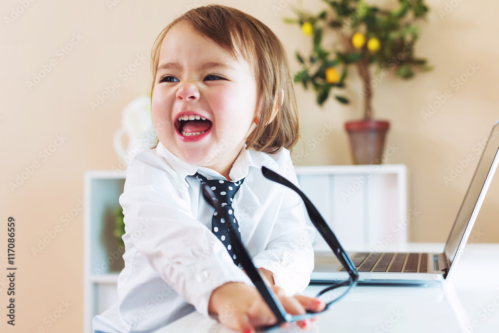 Happy toddler girl laughing while using a laptop