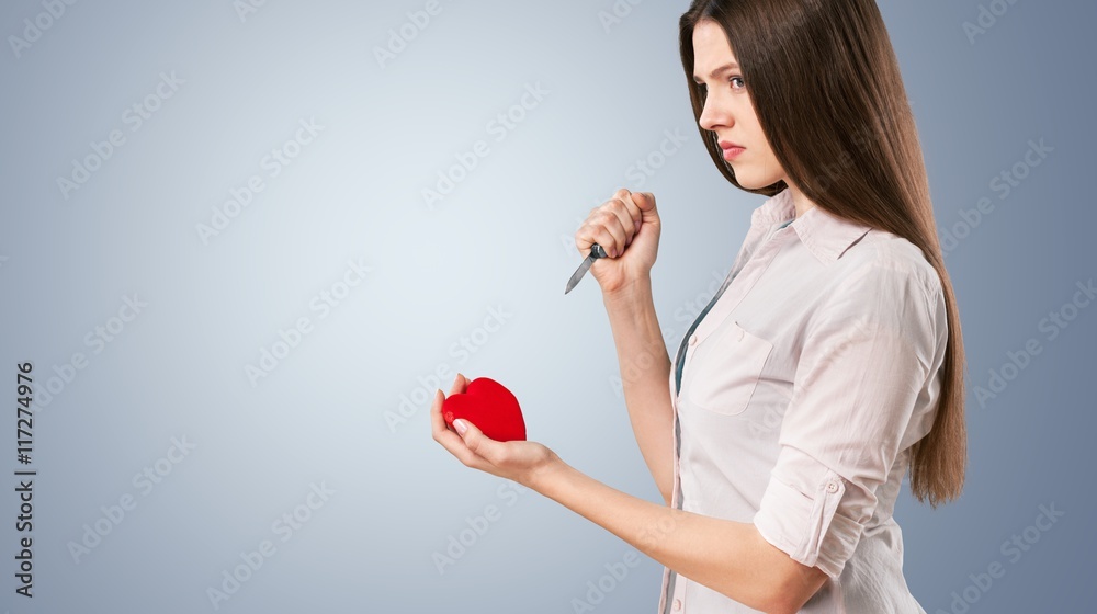 Sad girl is holding heart symbol.