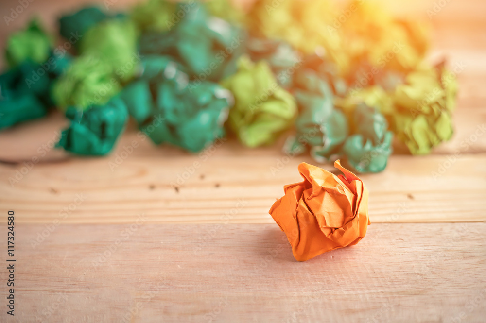 orange crumpled paper among the green paper