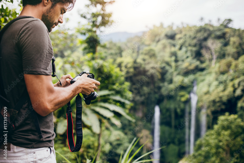 Male hiker photographing a waterfall in forest