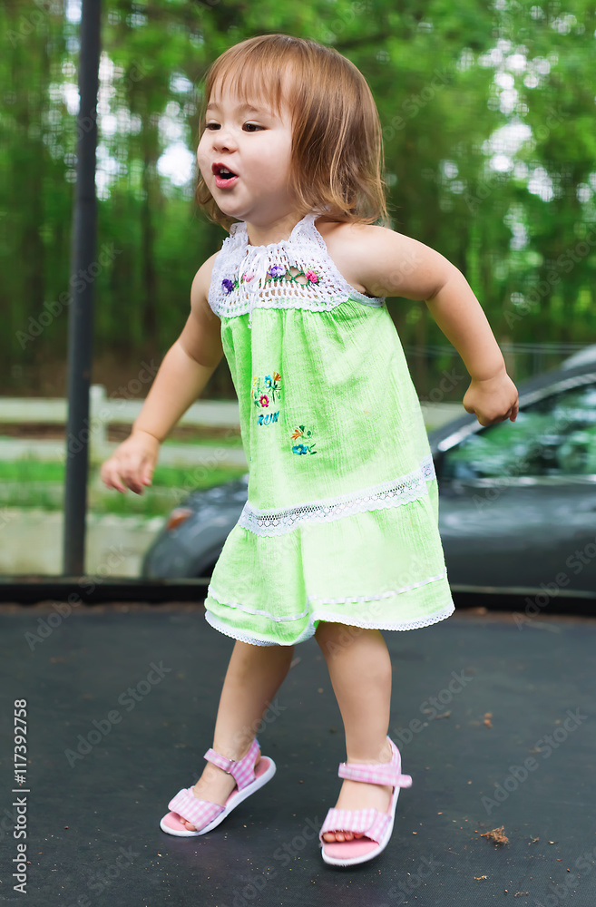 Happy toddler girl jumping on a trampoline