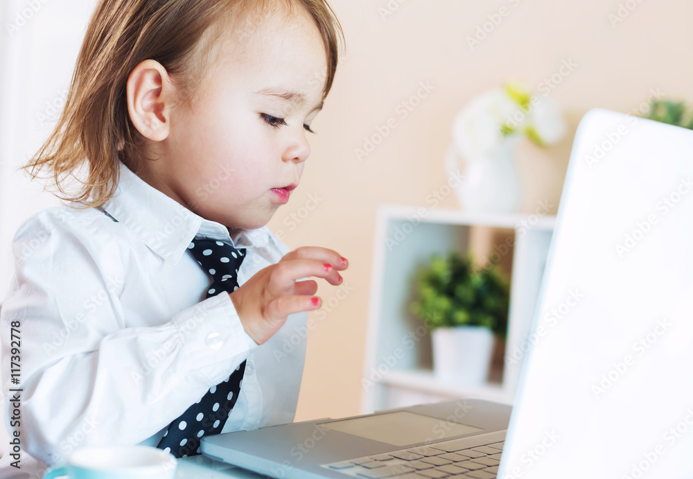 Serious toddler girl using a laptop