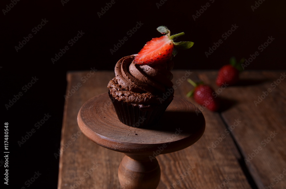 Chocolate cupcakes with strawberry and chocolate on a wooden table.