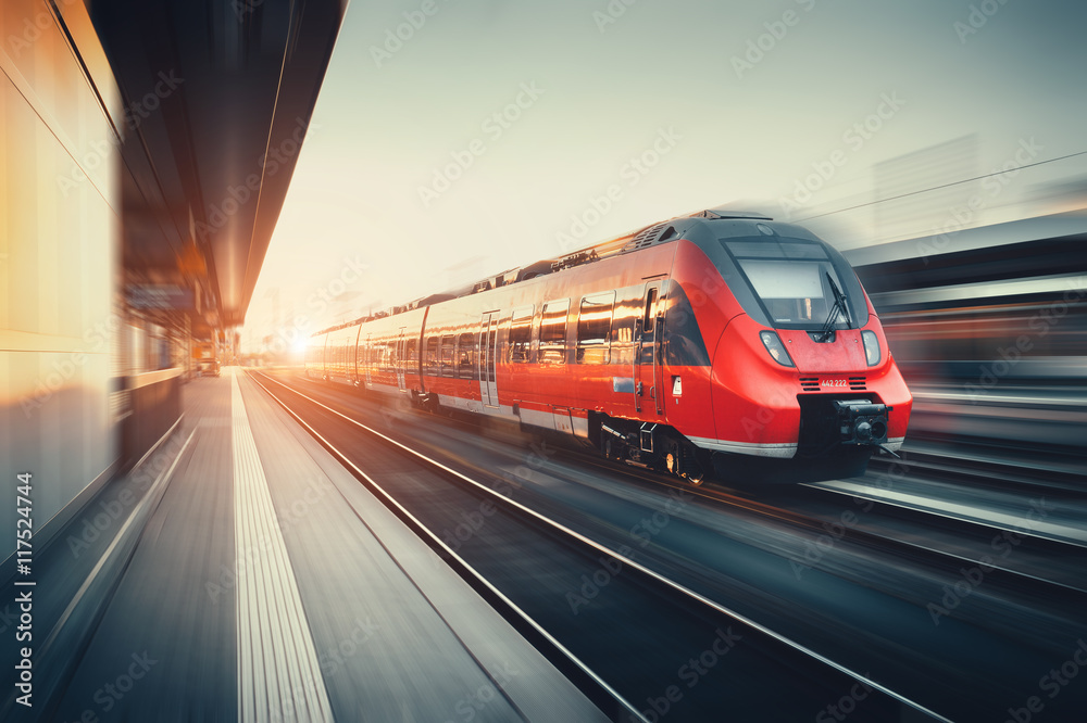 Beautiful railway station with modern red commuter train at suns