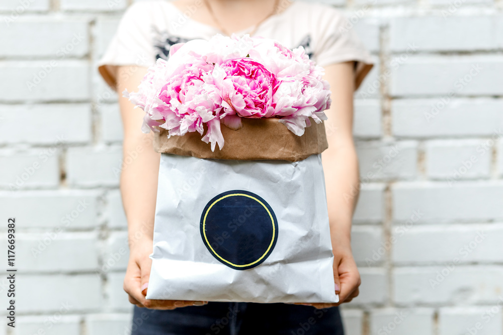 woman with bouquet of peonies in kraft bag