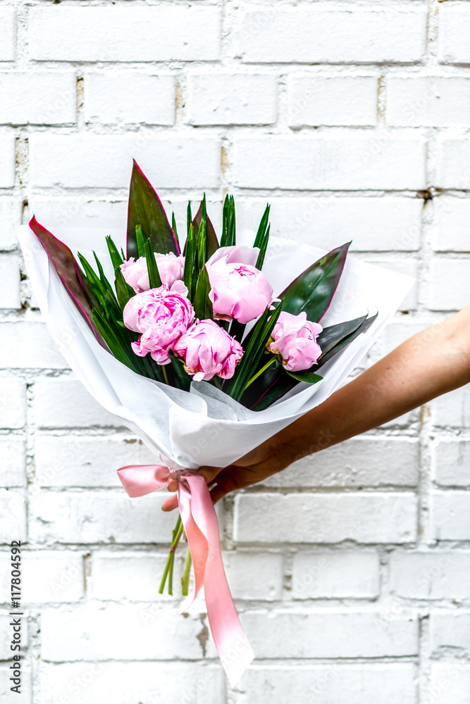 Bouquet of peonies in kraft paper on white background