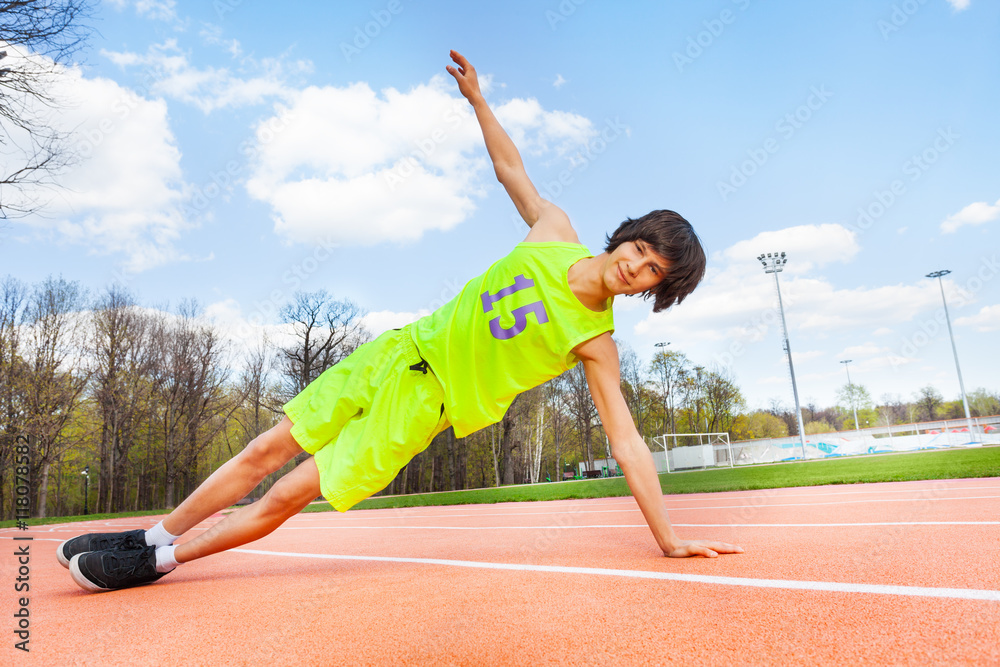 Active teenage boy holding a side plank outdoors