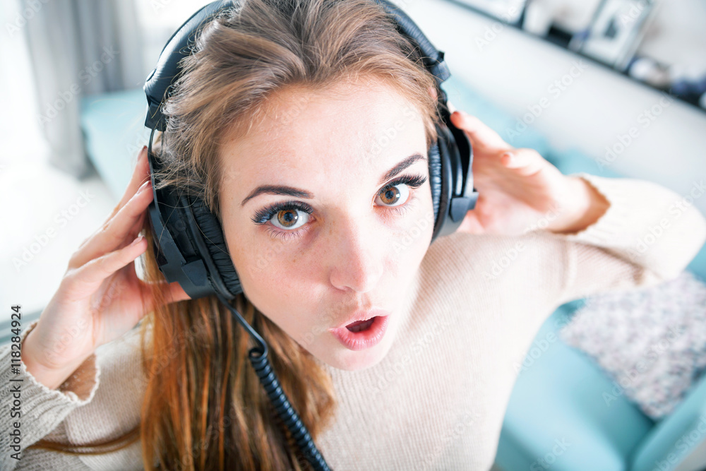 Portrait young woman with headphones listening to music at home