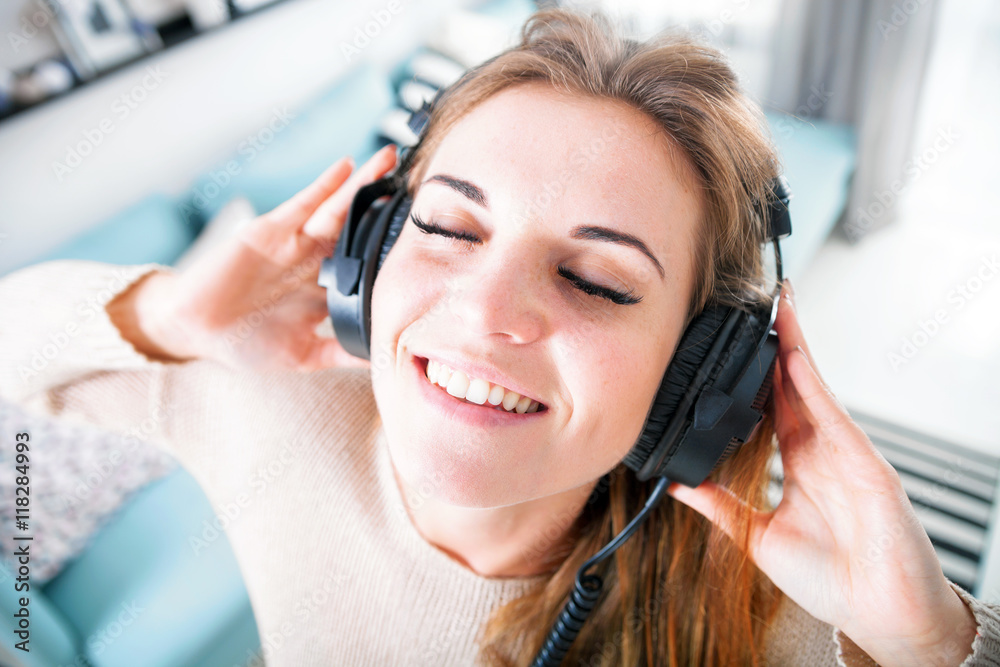 Portrait young woman with headphones listening to music at home