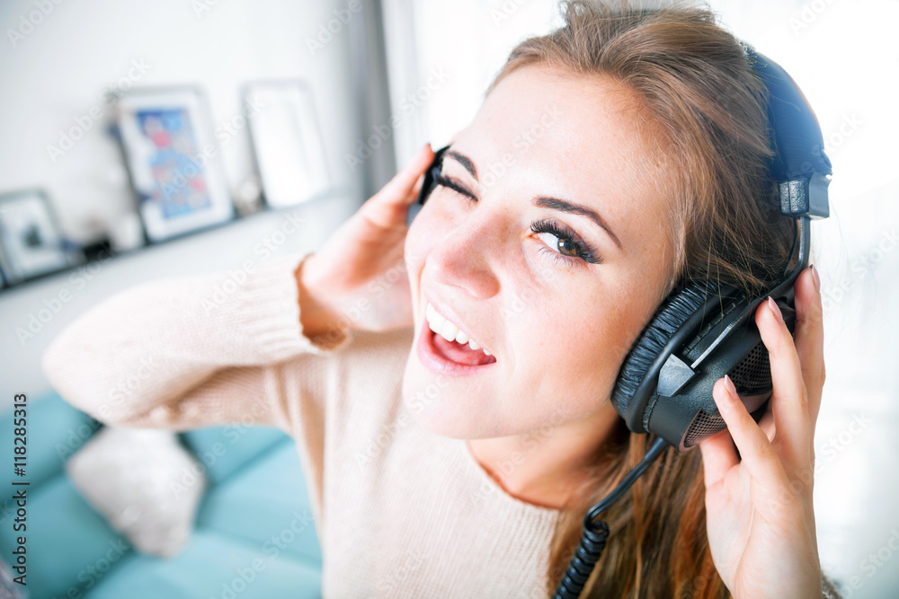 Woman with headphones singing and listening to music at home