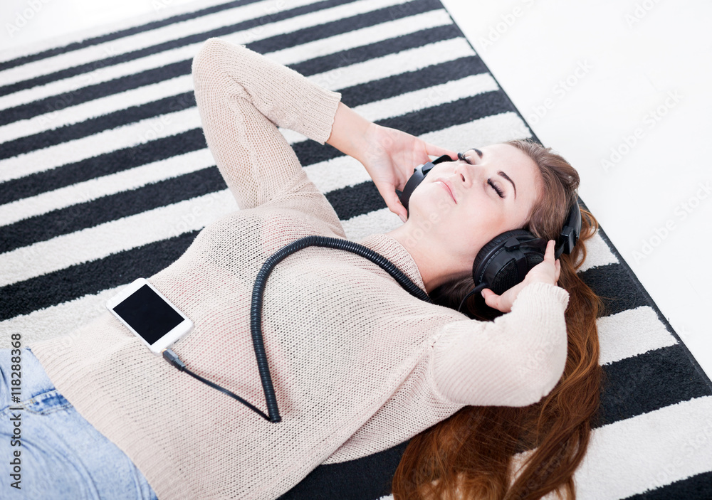 Woman with headphones lying and listening to music at home