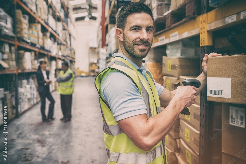 Warehouse worker scanning box while smiling at camera