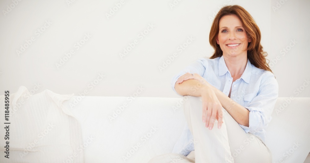 Smiling mature woman sitting on sofa