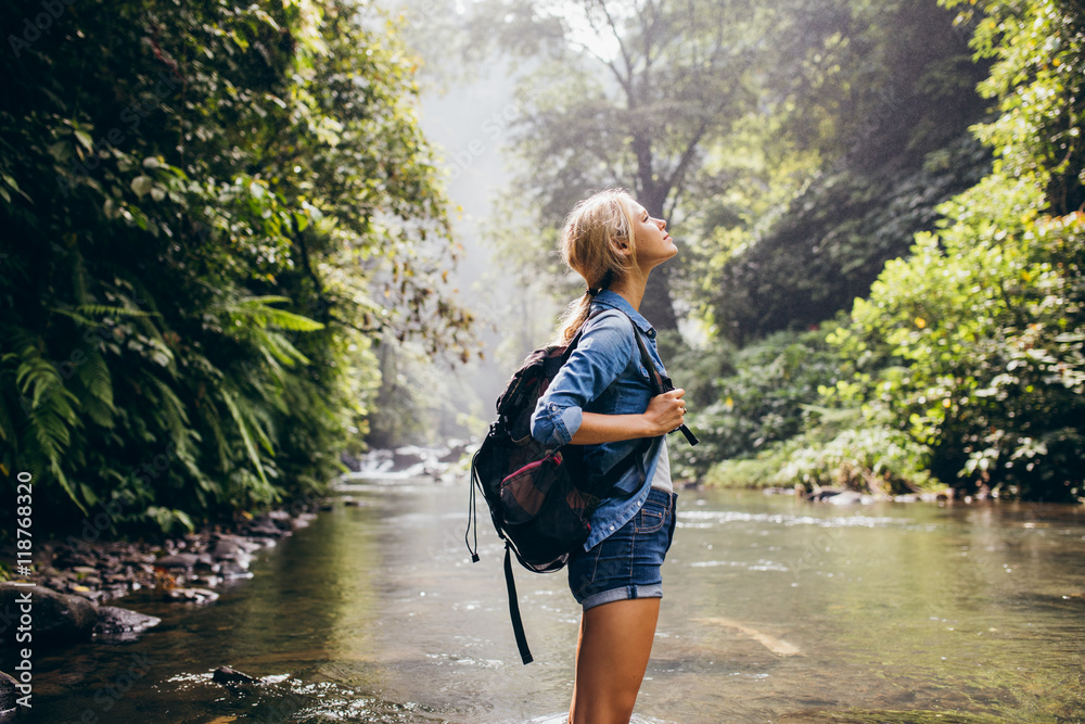 Relaxed female hiker standing by the stream