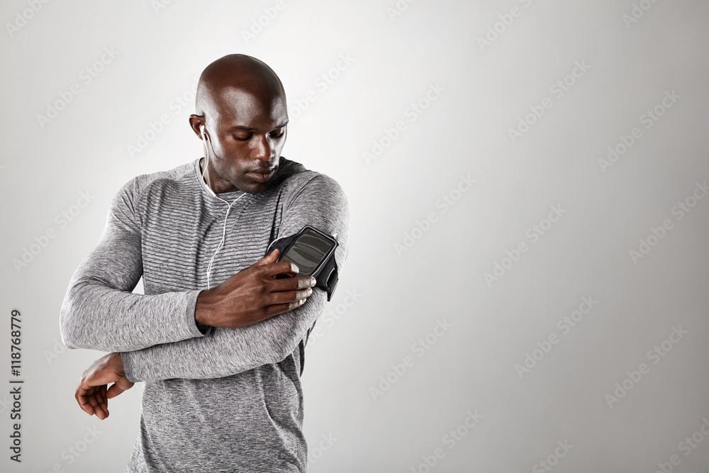 African muscular man listening to music on mobile phone