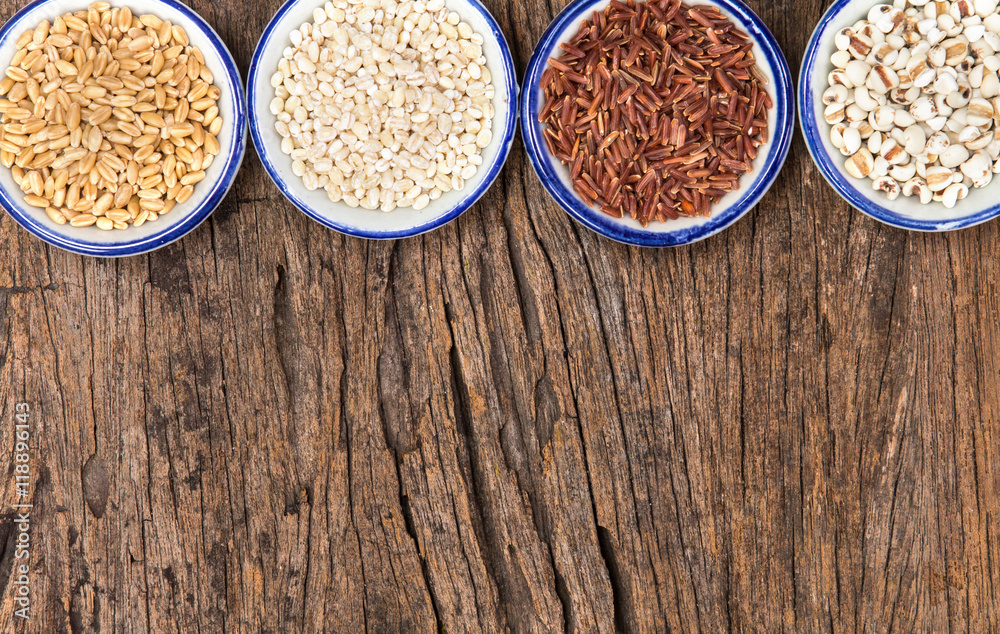 Variety of grain rice in cup on natural wooden background