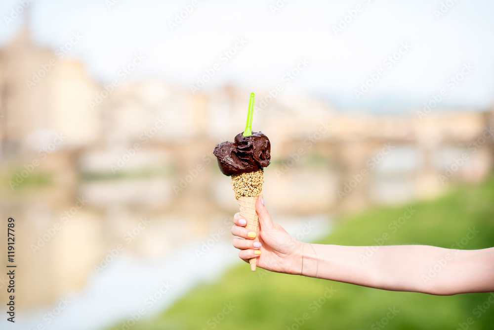 佛罗伦萨城市背景中女性手持华夫饼蛋筒巧克力冰淇淋。意大利传统